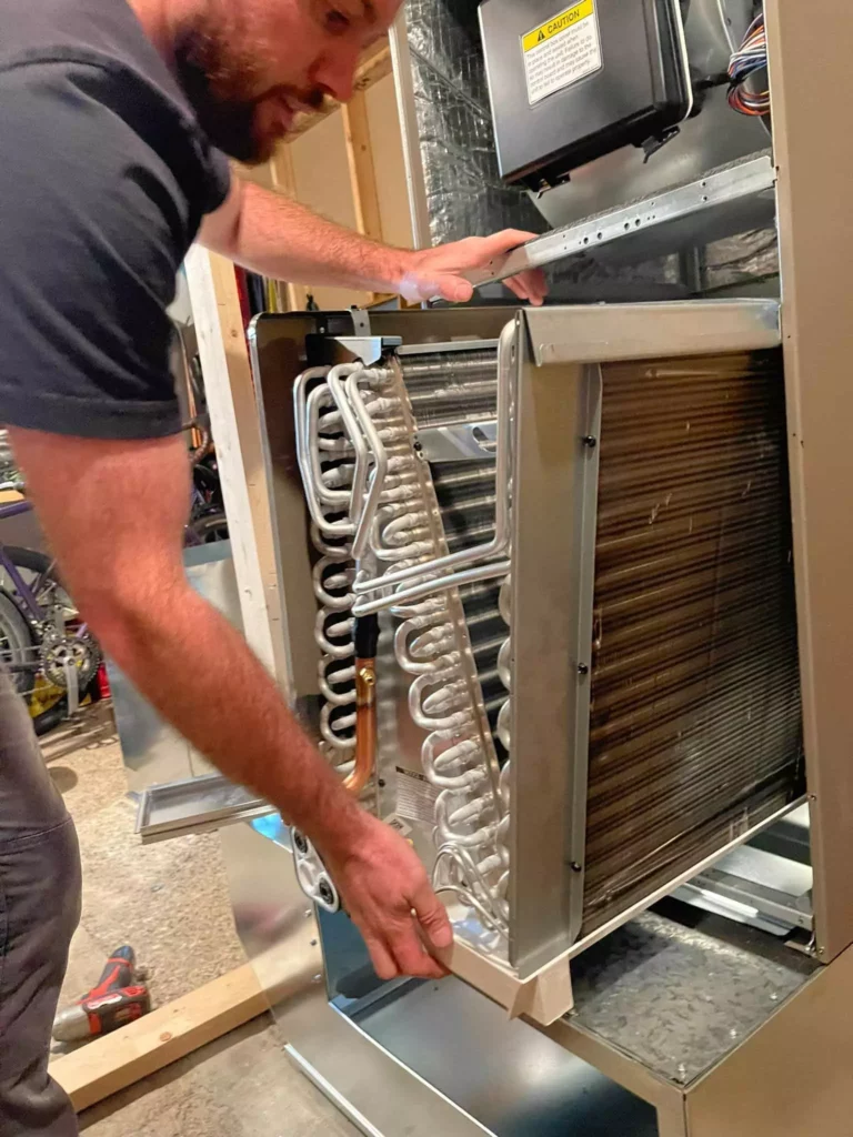 Phyxter HVAC tech installing a new evaporator coil in an indoor air handler