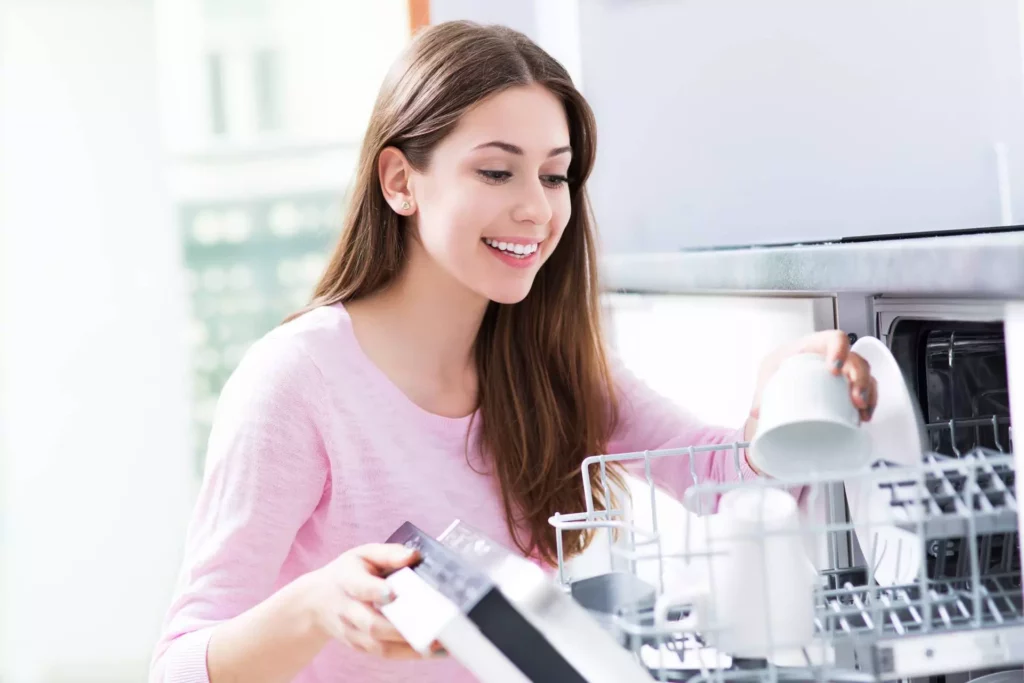 young woman loading dishwasher