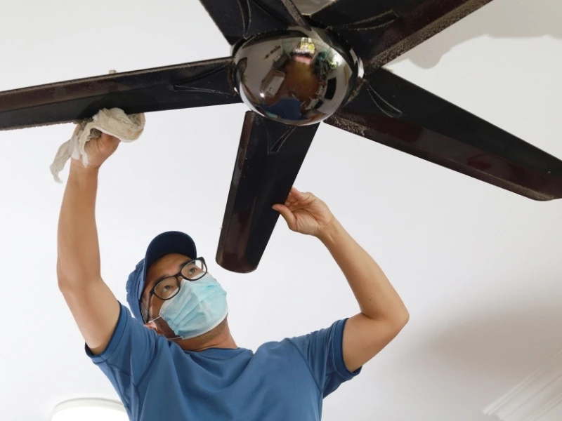 homeowner cleaning ceiling fan