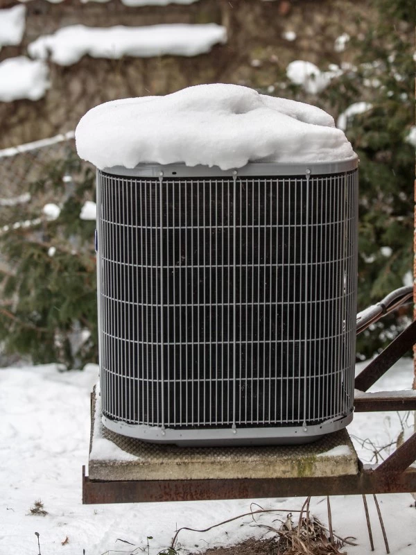 Outdoor AC condenser covered in snow